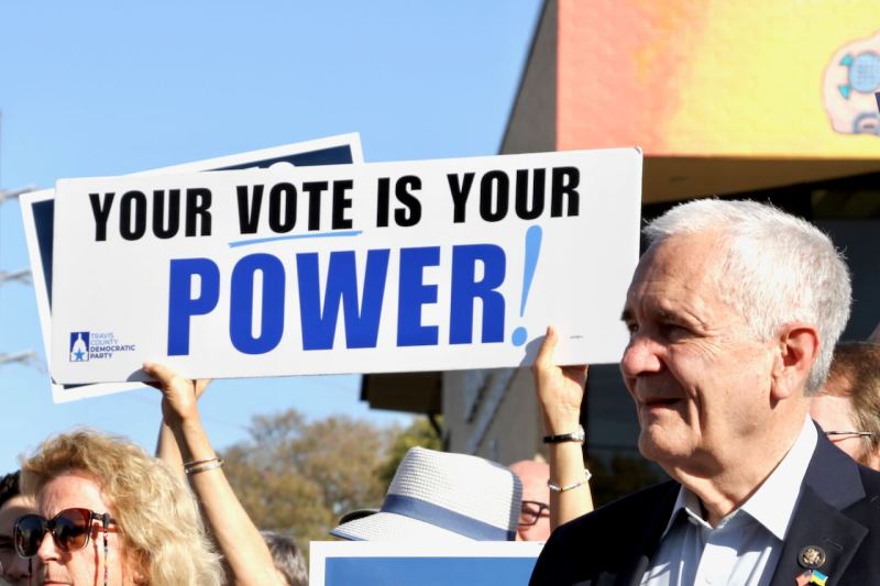 US Rep. Lloyd Doggett next to a sign that says, "Your vote is your power."