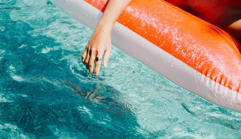 Permit requests for pools in Corpus Christi remain about the same despite ongoing drought. Photo shows a hand in a pool from a floating swimmer