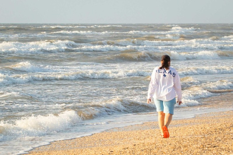 A woman walks along the beach, taking one of those Texas beach vacations