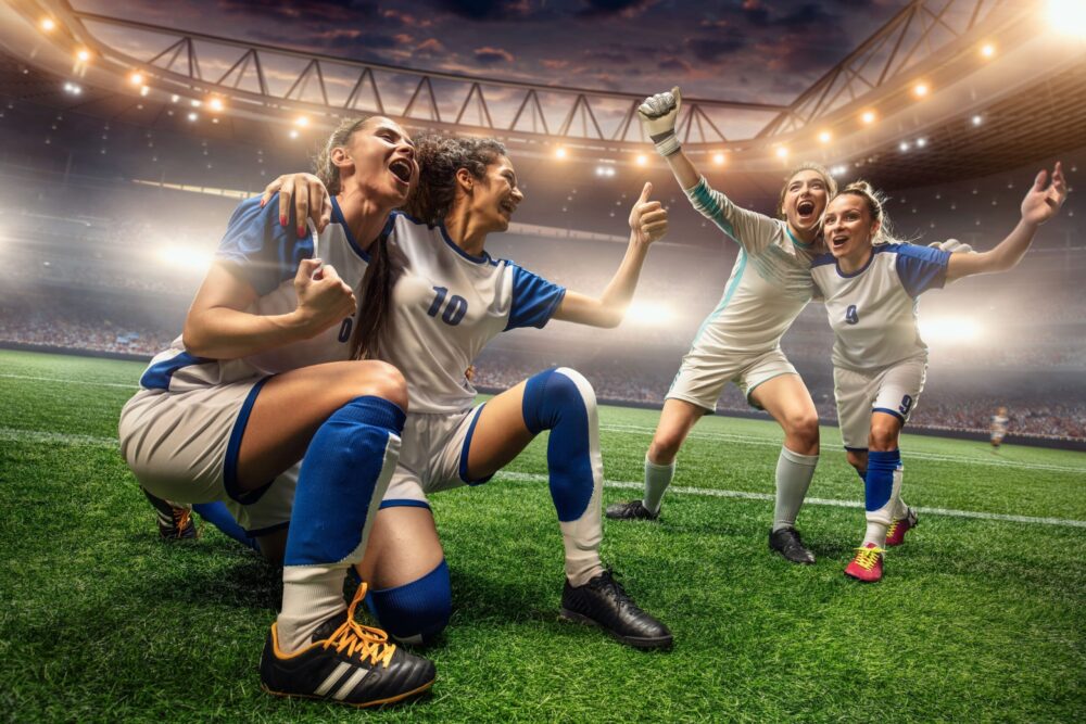 Happy Female Soccer players on a professional soccer stadium. Girls Team emotionally celebrates victory.