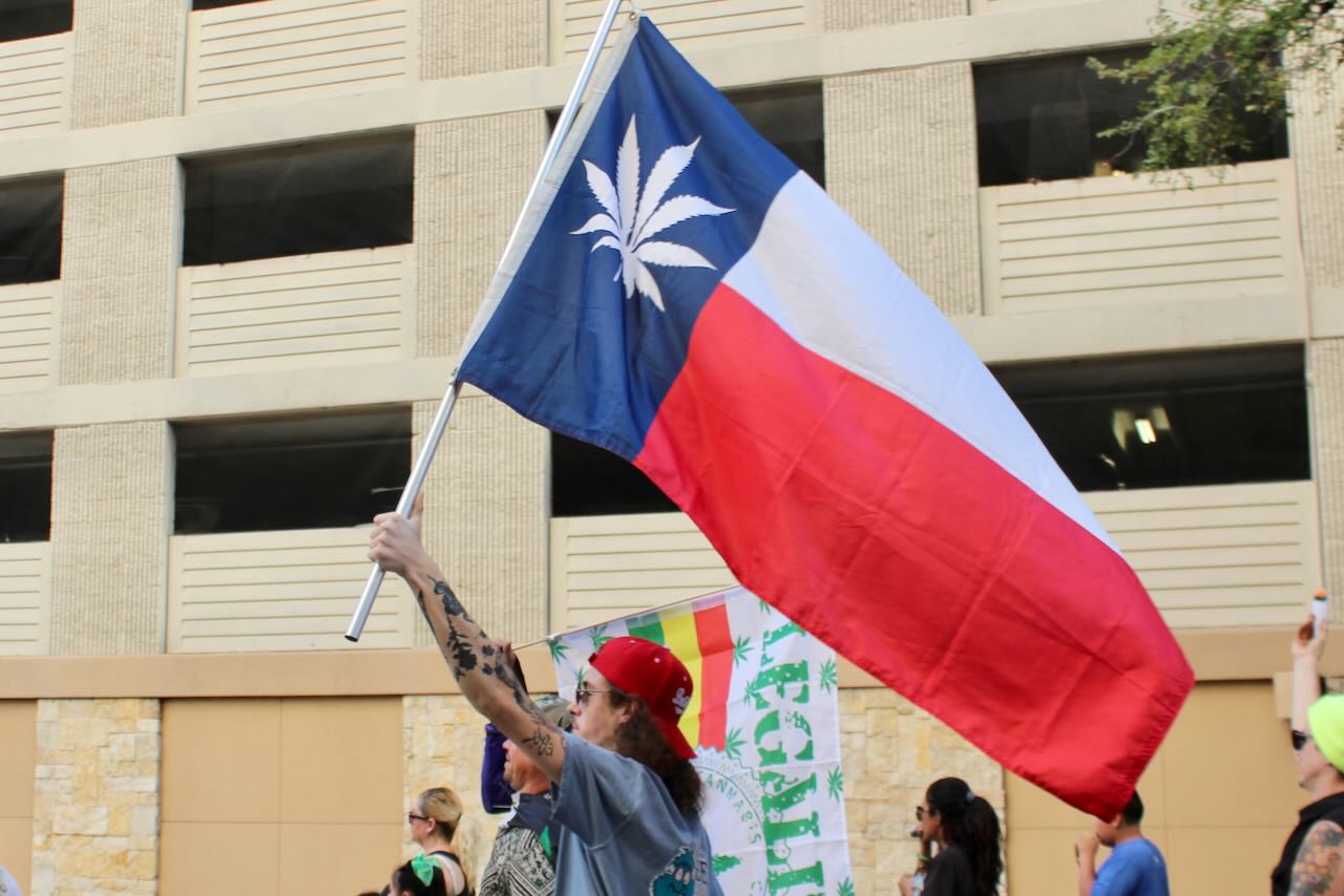 Man holds Texas flag with marijuana leaf replacing the star