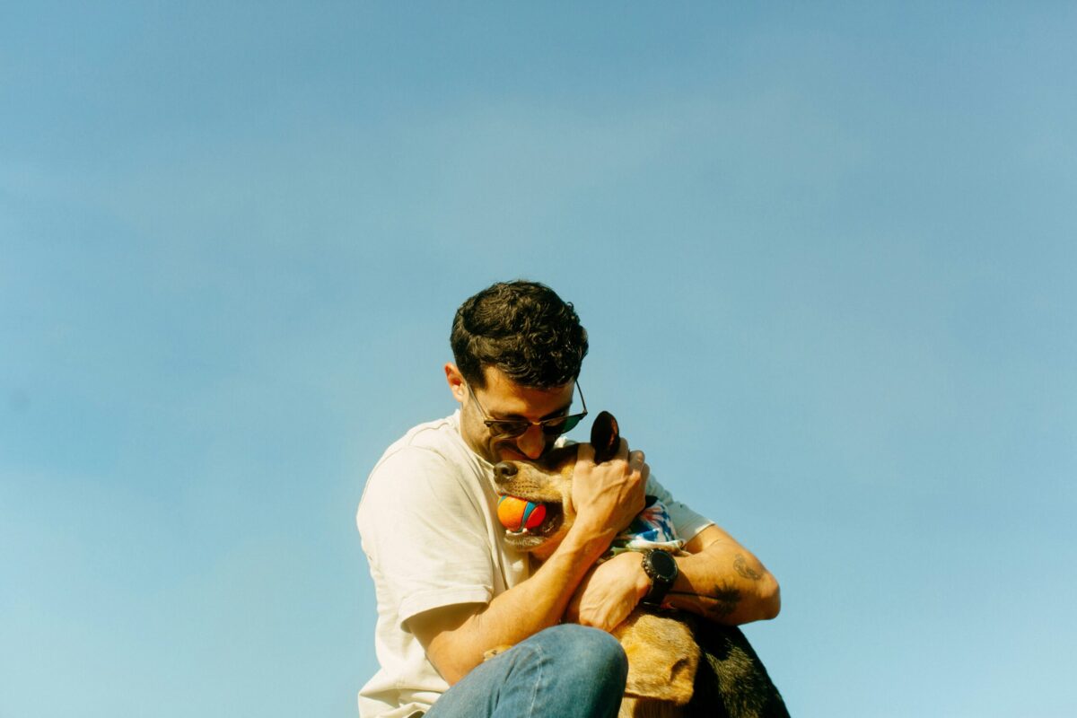 a man squats down to hug his dog close