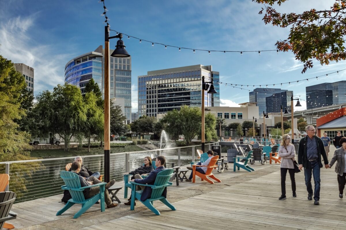 people sit and saunter along plano's waterfront boardwalk.