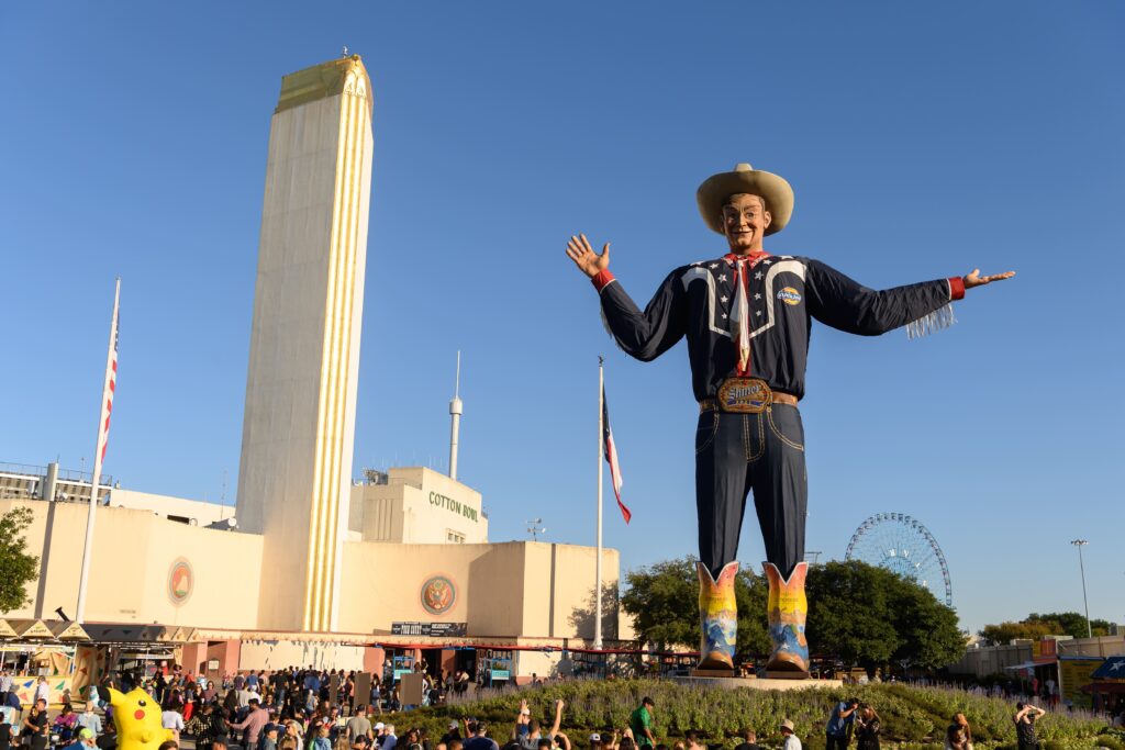 texas-state-fair an enormous statue of a cowboy looks over the crowd at the texas state fair