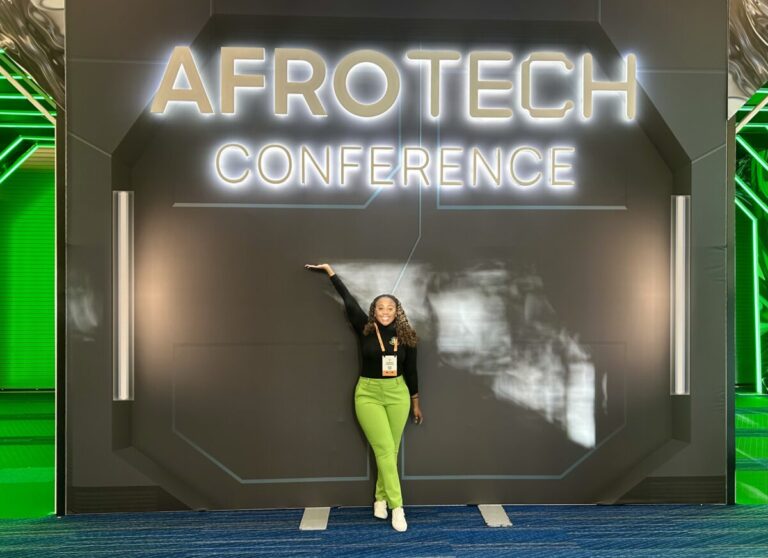 woman standing in front of AfroTech sign