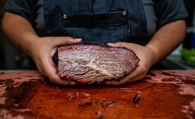 A butcher shop worker holding a piece of beef