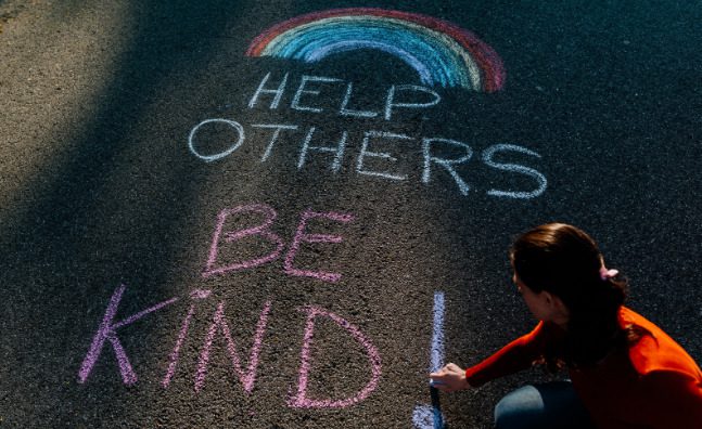 A sign that says "help others be kind," written in chalk.
